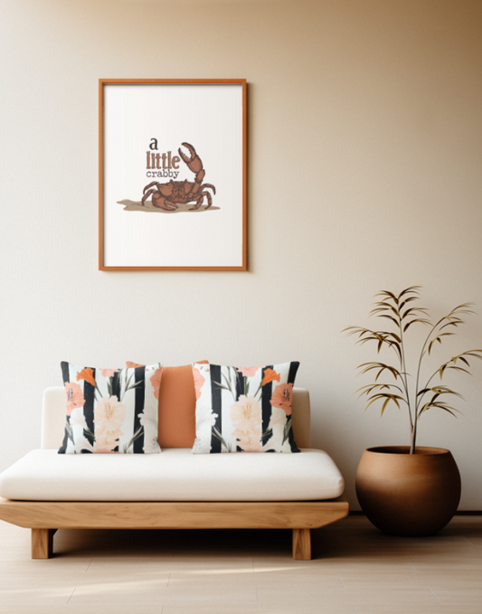 Zwei quadratische Baumwoll Kissen mit modernem, floralem Muster platziert auf einem Sofa im Japandi Stil. Das Design zeigt große, elegante Blüten in Pfirsich, leuchtendem Orange und Cremeweiß sowie schmale grüne Blätter. Der Hintergrund besteht aus kontrastreichen, vertikalen Streifen in Schwarz und Weiß.
