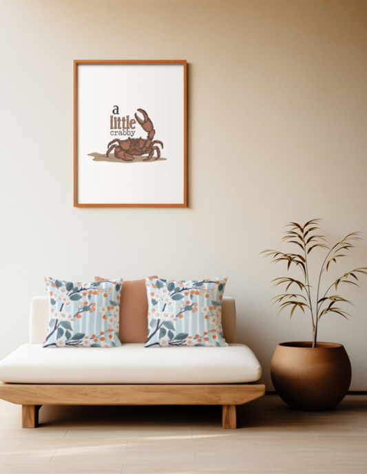 Zwei quadratische Baumwoll Kissen mit Orangenblüten-Muster platziert auf einem Sofa im Japandi Stil. Das Design zeigt dunkle Zweige mit kleinen weißen Orangenblüten, graublauen Blättern und runden, orangefarbenen Früchten. Der Hintergrund besteht aus feinen, vertikalen Streifen in Hellblau und Weiß mit einer leichten Textur.