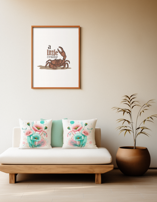 Zwei quadratische Baumwoll Kissen mit modernem Mohnblumen-Muster platziert auf einem Sofa im Japandi Stil. Das Design zeigt ein kunstvolles Arrangement aus rosa und türkisfarbenen Mohnblüten, grünen Kapseln, feinen goldenen Blätter-Linienzeichnungen und abstrakten Kreisen in Türkis und Rosa auf cremefarbenem Grund.