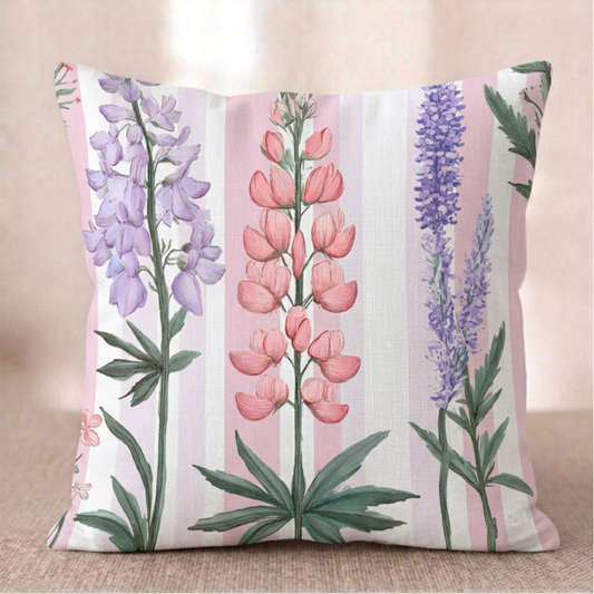 Ein quadratischer Baumwoll - Kissen-bezug mit botanischem Lupinen-Muster vor einem hellen Hintergrund. Das Design zeigt vertikal wachsende, detailreiche Lupinenblüten in Rosa, Hellviolett und Dunkelblau mit sternförmigen grünen Blättern am Stielansatz. Der Hintergrund besteht aus gleichmäßigen, vertikalen Streifen in zartem Rosa und Weiß.