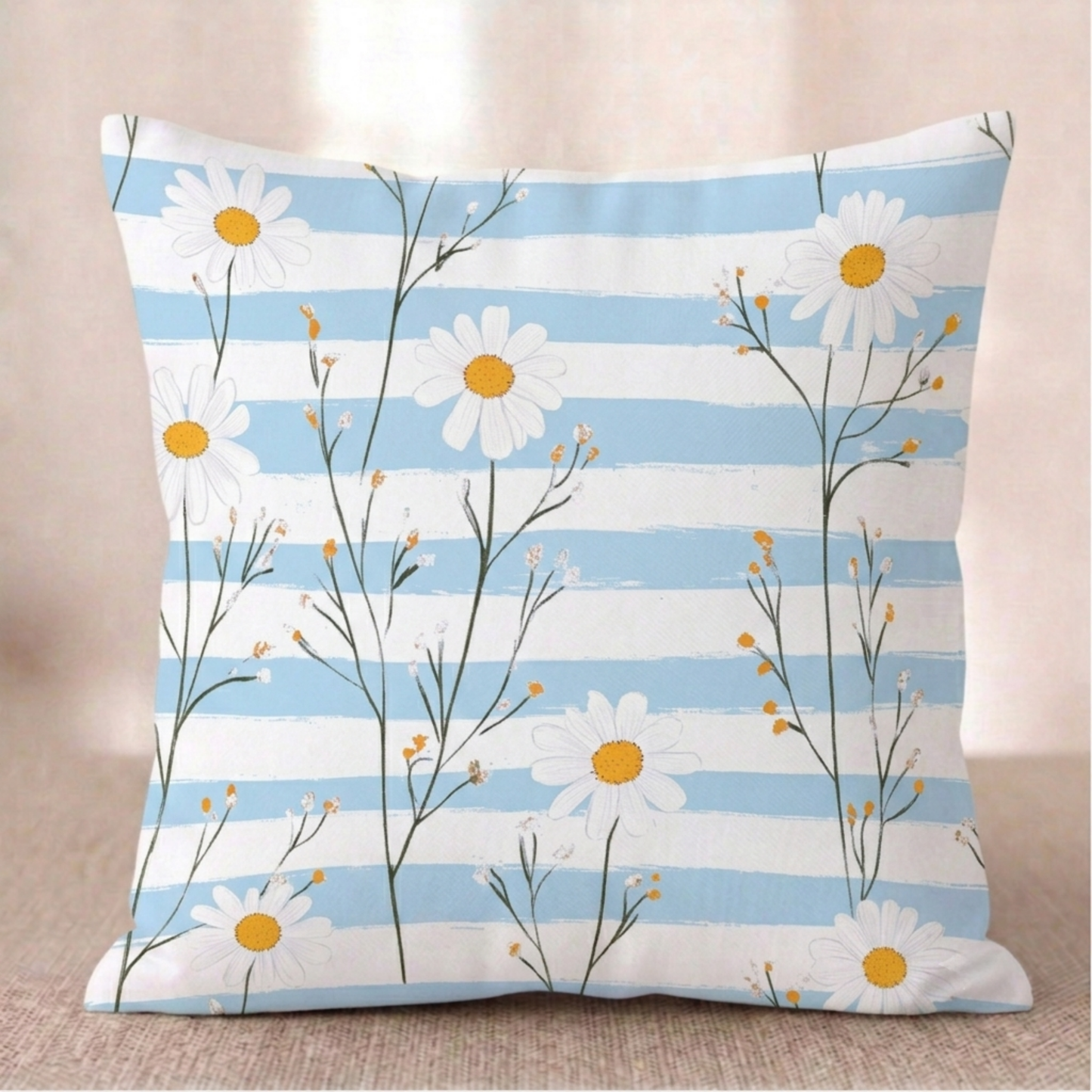 Ein quadratischer Baumwoll - Kissen-bezug mit Gänseblümchen-Muster vor einem hellen Hintergrund. Das Design zeigt filigrane, grüne Stängel mit weißen Gänseblümchen und kleinen, gelb-orangefarbenen Knospen. Der Hintergrund besteht aus horizontal verlaufenden Streifen in Hellblau mit einer leichten Pinselstruktur und Weiß.