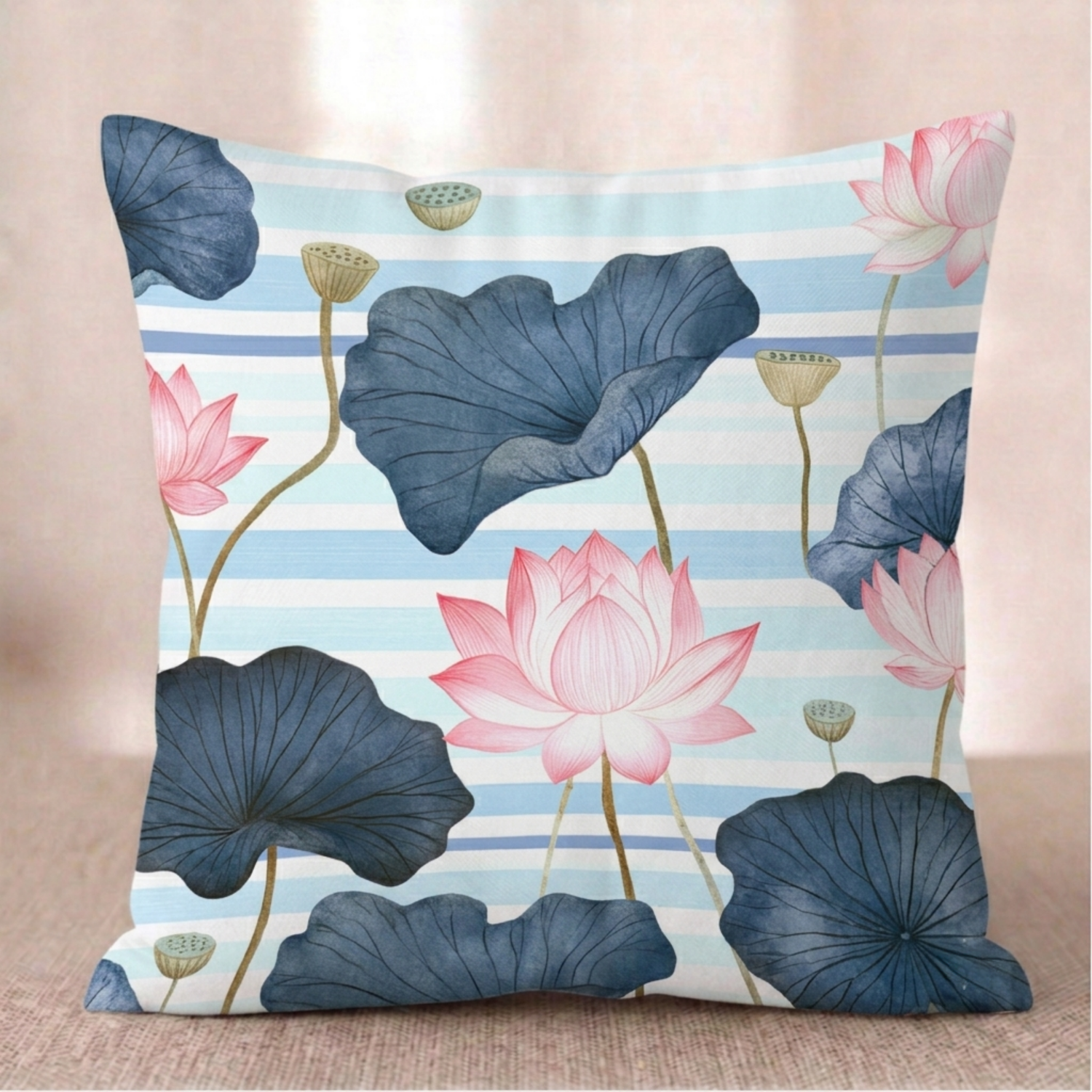 Ein quadratischer Baumwoll Kissen-bezug mit Lotus-Motiv in den Größen 45x45 cm und 55x55 cm vor hellem Hintergrund. Das Design zeigt rosa Lotusblüten, große dunkelblaue Blätter und goldene Samenkapseln auf einem Hintergrund aus hellblau-weiß gestreiften Aquarell-Querstreifen.