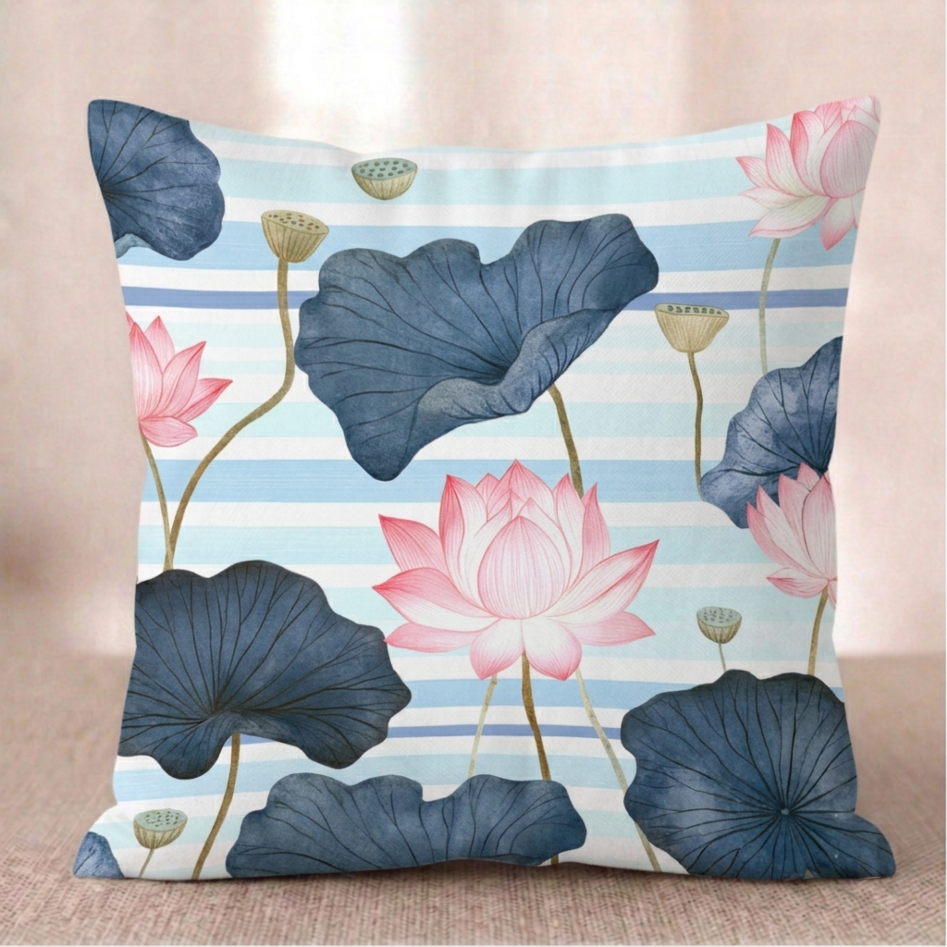 Ein quadratischer Baumwoll Kissen-bezug mit Lotus-Motiv in den Größen 45x45 cm und 55x55 cm vor hellem Hintergrund. Das Design zeigt rosa Lotusblüten, große dunkelblaue Blätter und goldene Samenkapseln auf einem Hintergrund aus hellblau-weiß gestreiften Aquarell-Querstreifen.