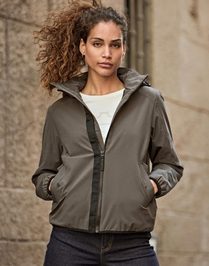 Damen Adventure Jacke in Dark Olive mit glatter Oberfläche und leicht taillierter Passform. Mit Kapuze, hochschließendem Kragen, Frontreißverschluss und seitlichen Eingriff Taschen.
