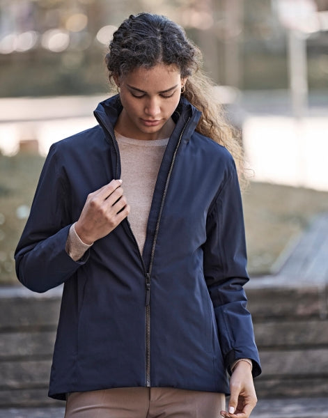 Eine Damen All  Weather Jacke  in  dunkelblau mit geradem, längerem Schnitt bis über die Hüfte. Schlichtes Design mit hochstehendem Kragen, verdecktem Frontreißverschluss und zwei seitlichen Reißverschlusstaschen.