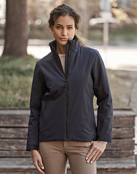 Eine Damen All  Weather Jacke  in  schwarz mit geradem, längerem Schnitt bis über die Hüfte. Schlichtes Design mit hochstehendem Kragen, verdecktem Frontreißverschluss und zwei seitlichen Reißverschlusstaschen.