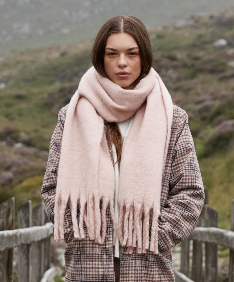 Oversized Schal für Damen in Blush Pink aus weichem, voluminösem Material mit leicht strukturierter Oberfläche, breiter Form und langen, dicht gesetzten Fransen an beiden Enden.
