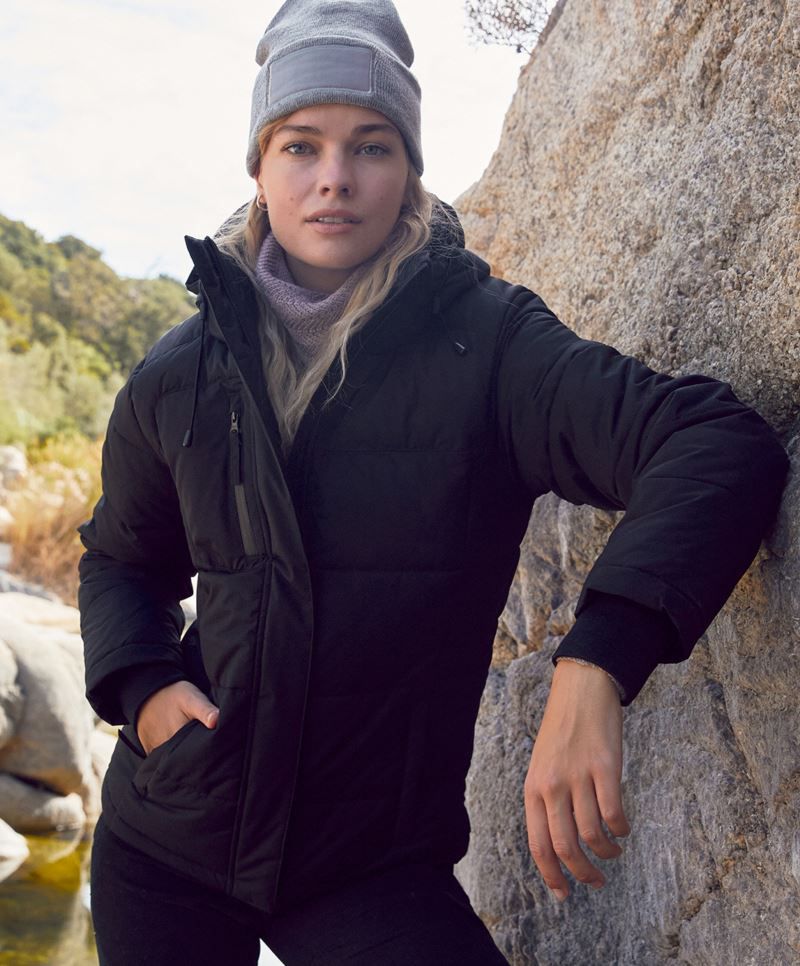 Damen Colorado Winterjacke in Schwarz mit horizontaler Steppung und hüftlangem Schnitt. Die Jacke hat eine Kapuze, einen durchgehenden Frontreißverschluss und zwei seitliche Eingriff Taschen.