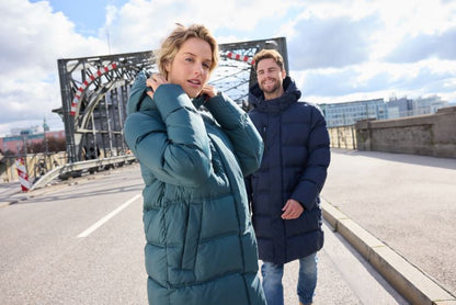Damen Pufferjacke in Smokey Green mit gleichmäßiger horizontaler Steppung und voluminöser Wattierung. Knielanger Schnitt mit Kapuze, hochschließendem Kragen, durchgehendem Frontreißverschluss und seitlichen Eingriff Taschen.