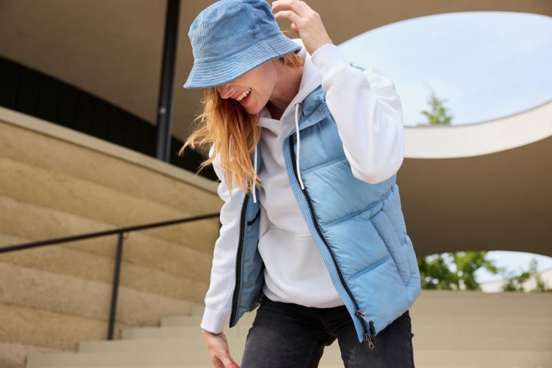 Damen Puffer Weste n Milky Blue mit gleichmäßiger horizontaler Steppung und voluminöser Wattierung. Hüftlanger Schnitt und hochschließendem Kragen, durchgehendem Frontreißverschluss und seitlichen Eingriff Taschen.