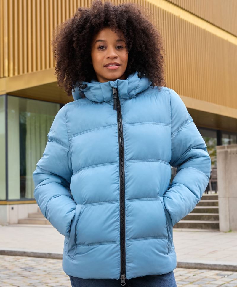Damen Pufferjacke in Milky Blue mit gleichmäßiger horizontaler Steppung und voluminöser Wattierung. Hüftlanger Schnitt mit Kapuze, hochschließendem Kragen, durchgehendem Frontreißverschluss und seitlichen Eingriff Taschen.