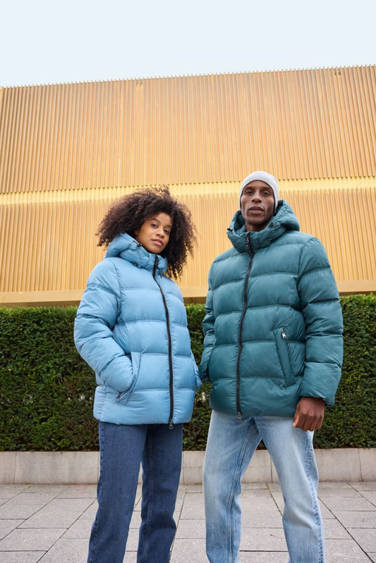 Damen Pufferjacke in Milky Blue mit gleichmäßiger horizontaler Steppung und voluminöser Wattierung. Hüftlanger Schnitt mit Kapuze, hochschließendem Kragen, durchgehendem Frontreißverschluss und seitlichen Eingriff Taschen.