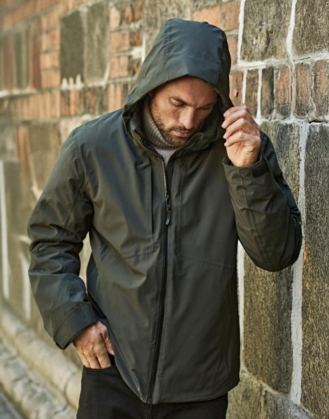 Eine Herren All  Weather Winter Jacke mit Kapuze  in  Asphalt mit geradem, längerem Schnitt bis über die Hüfte. Schlichtes Design mit hochstehendem Kragen, verdecktem Frontreißverschluss und zwei seitlichen Reißverschlusstaschen.