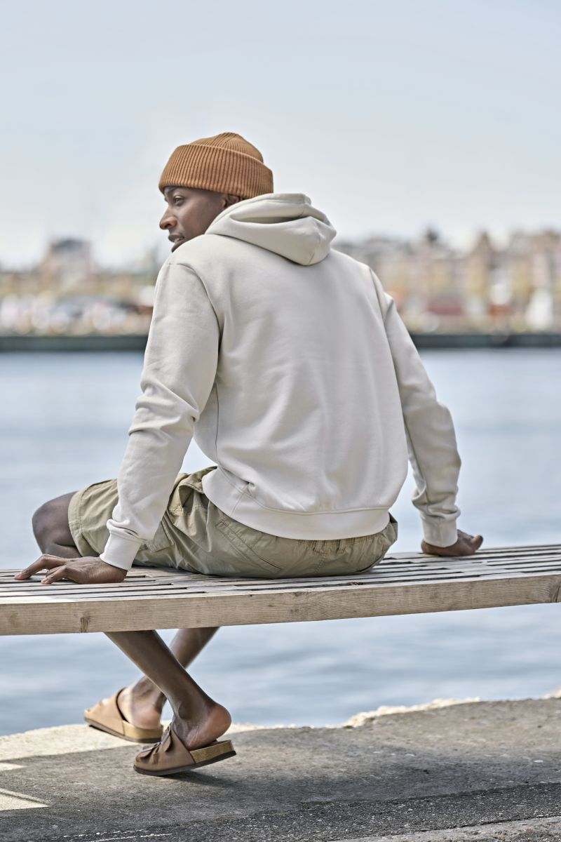 Herren Heavy Hoodie in Cement mit lässiger Passform und cleanem, einfarbigem Design. Mit großer Kapuze samt Kordelzug, langen Ärmeln, breiten Rippbündchen und klassischer Kängurutasche auf der Vorderseite.