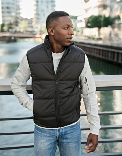 Herren Hybrid-Stretch-Weste mit wattierter, quer gesteppter Vorderseite in schwarz und seitlichen Einsätzen. Die Weste ist körpernah geschnitten und hat einen hohen Stehkragen sowie einen durchgehenden Front Reißverschluss.