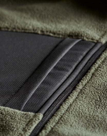 Mountain Fleecejacke in Deep Green/Black mit schwarzem Reißverschluss und dunklen Kontrastbesätzen an Brust, Schultern und Ärmeln. Die hüftlange Jacke ist körpernah geschnitten, hat einen hohen Kragen und seitliche Reißverschlusstaschen.