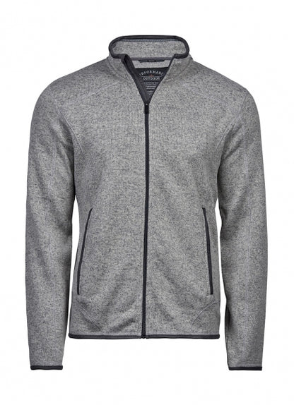 Graue Outdoor Fleece Jacke in geradem, körpernahem Schnitt. Die hüftlange Fleecejacke hat einen hohen Stehkragen, lange Ärmel und zwei seitliche Reißverschlusstaschen. Das schlichte Design wird durch dezente schwarze Details an Reißverschlüssen und Abschlüssen ergänzt.