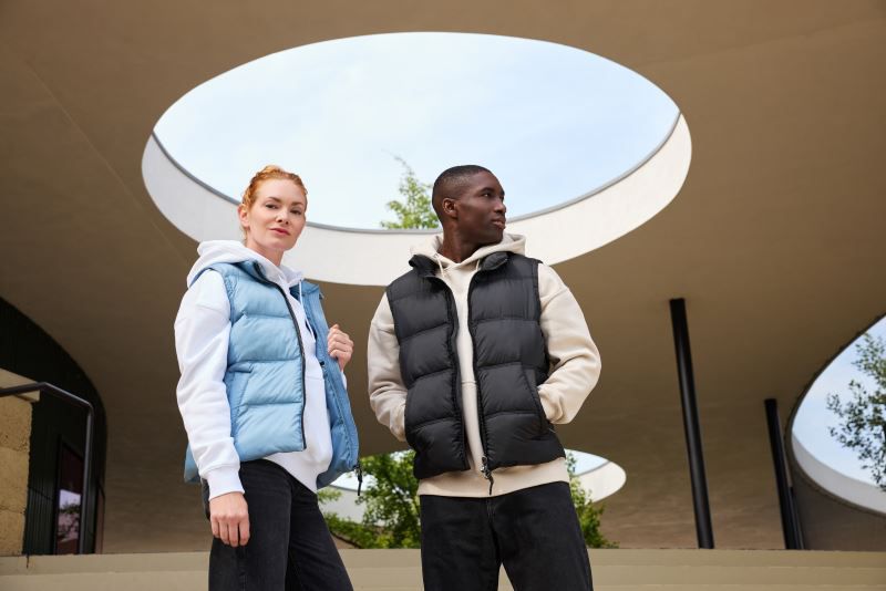 Herren Puffer Weste schwarz mit gleichmäßiger horizontaler Steppung und voluminöser Wattierung. Hüftlanger Schnitt und hochschließendem Kragen, durchgehendem Frontreißverschluss und seitlichen Eingriff Taschen.